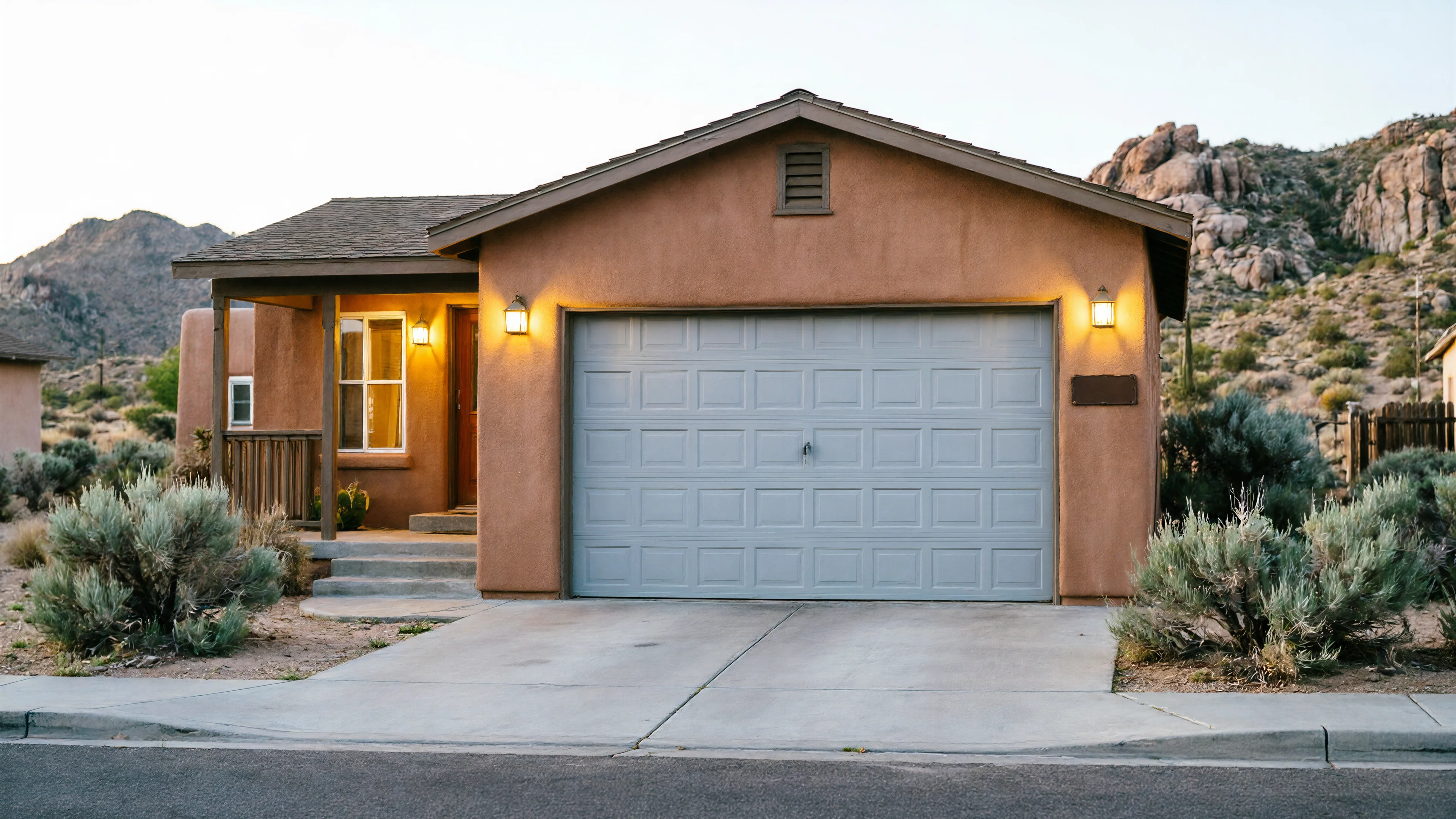 The house has a light gray garage door and a desert landscape.